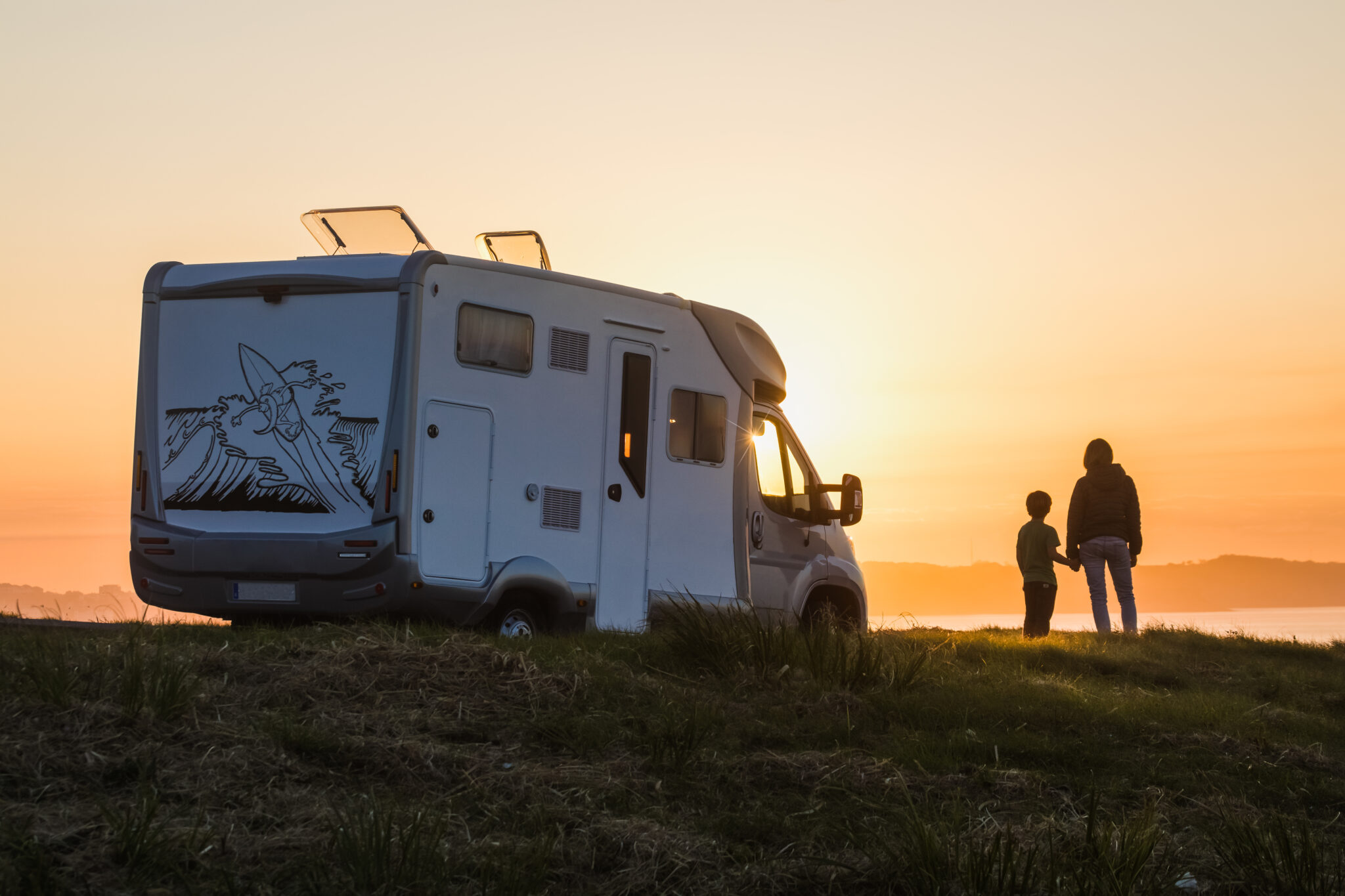 Familie vor einem Camper in der Natur